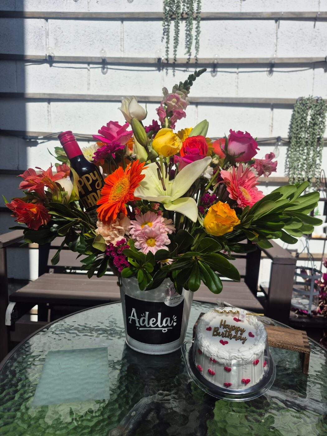 Arreglo floral colorido junto a un pastel de cumpleaños