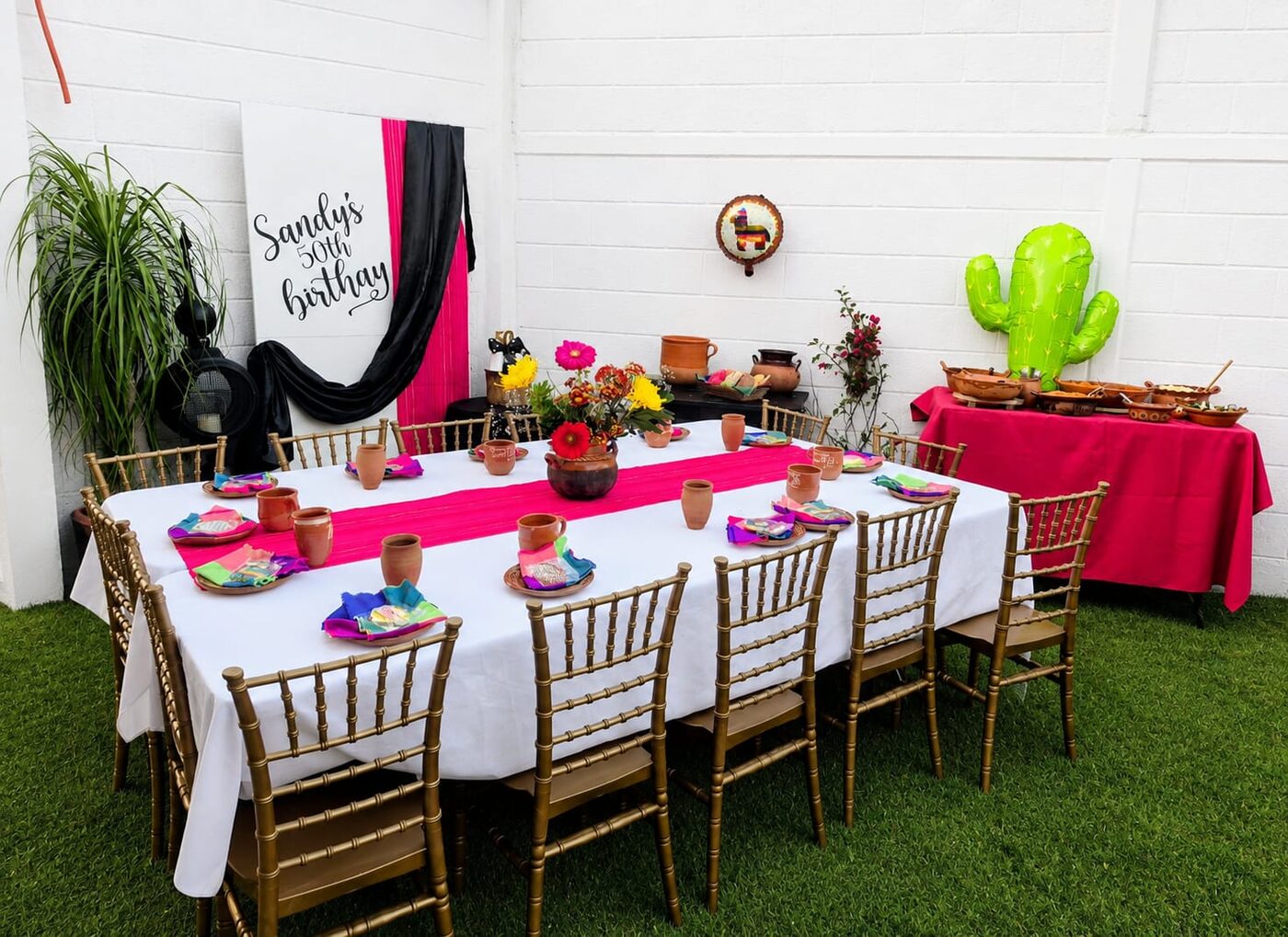 Mesa de evento decorada con manteles blancos y fucsias y centro floral